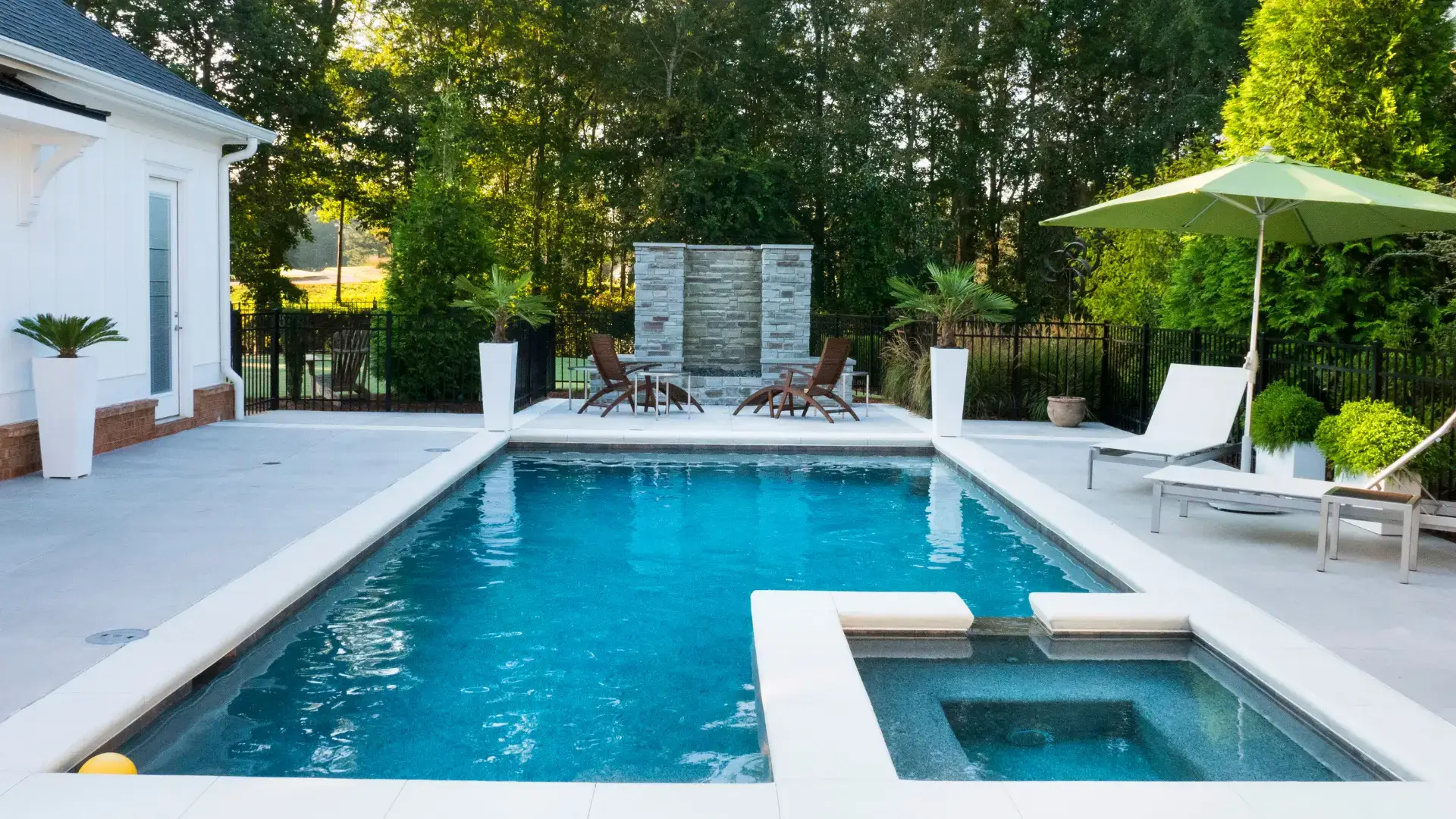 Luxury pool landscaping with drop-face paving coping and frameless glass fencing